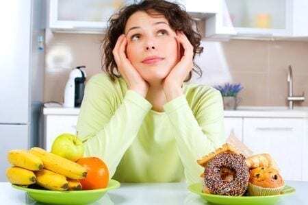 stop stress eating woman picture who is choosing between fruit and sugary foods but looking up at the ceiling mindfully