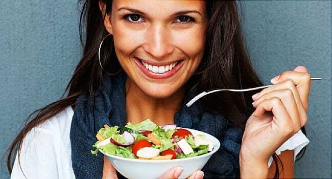 woman smiling while holding bowl of salad