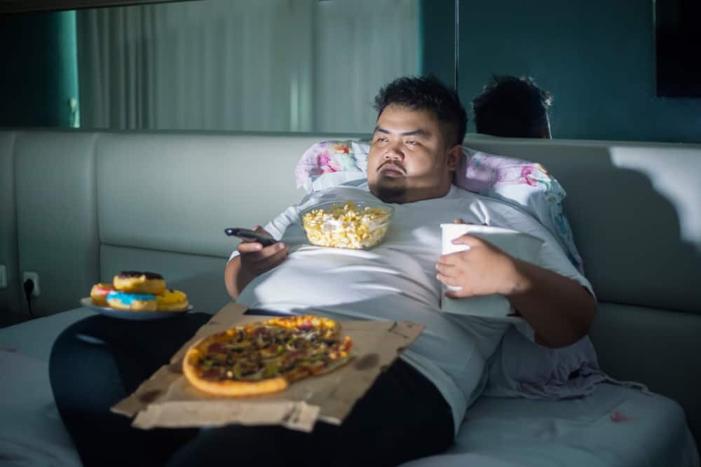 guy binge eating pizza on the couch